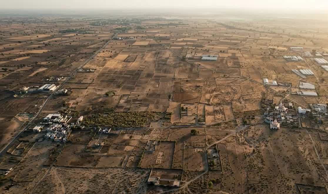 Aerial view of open farmland with field boundaries, a road and a few buildings — a representative image, not a specific place